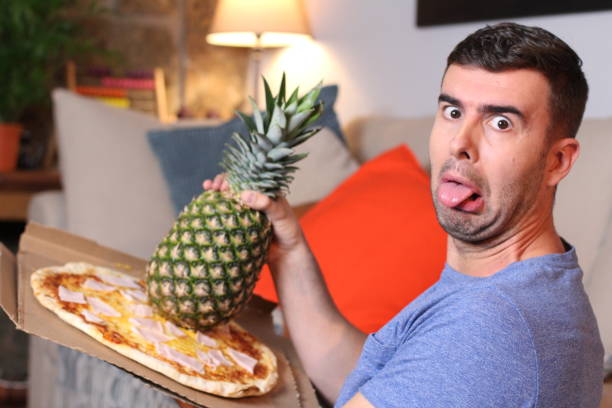 istock Grossed out man holding pineapple and pizza 1209862389