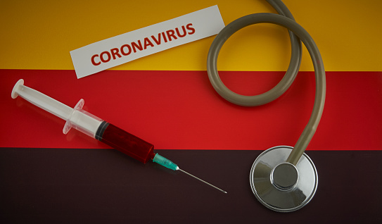 Stethoscope and syringe on Germany flag with coronavirus label