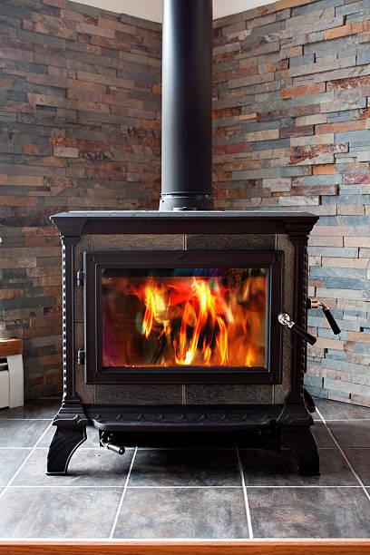 Burning Cast Iron Wood Stove Heating A new cast iron wood stove burning hot with slate tile. wood burning stove stock pictures, royalty-free photos & images