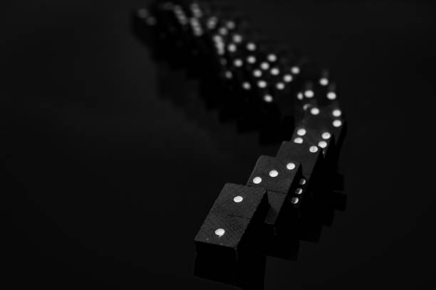 istock Black vintage falling dominoes on a black background, selective focus. WB photo. 1209865223