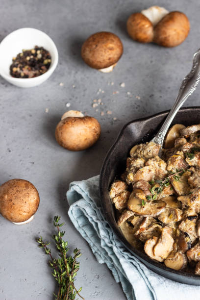 istock Meat stewed with mushroom and thyme in a cast-iron pan.  Grey concrete background. Copy space. 1209865371
