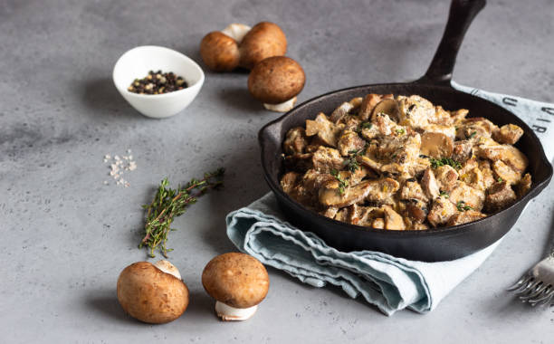 istock Meat stewed with mushroom and thyme in a cast-iron pan.  Grey concrete background. Copy space. 1209866041