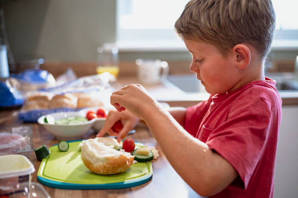 Boy Making a Sandwich A side view shot of a young boy making himself a sandwich in the kitchen. making a sandwich stock pictures, royalty-free photos & images