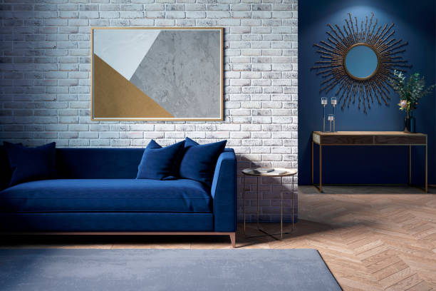 das innere eines modernen wohnzimmers mit einem dunkelblauen sofa neben einer ziegelwand, an der ein horizontales plakat hängt, im hintergrund sieht man einen spiegel über dem schrank mit blumen. - living room blue sofa carpet stock-fotos und bilder