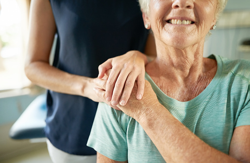 Close-up shot of caregiver putting hand on the shoulder of senior woman patient