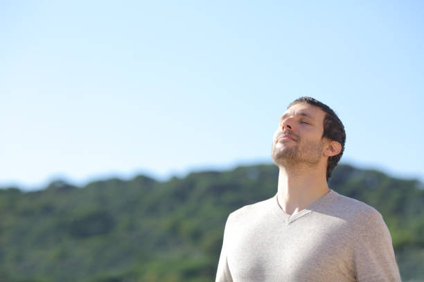 hombre respirando aire fresco cerca de las montañas - exhalar fotografías e imágenes de stock