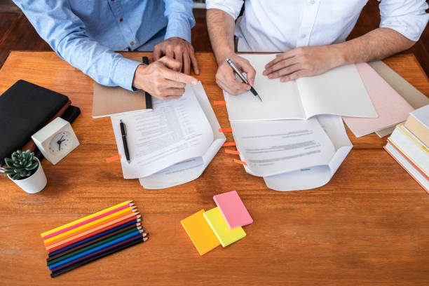 istock Teaching helping and study course, Team of young teacher or tutor helps students to learning in classroom for homework a test or exam at desk with papers 1209867714