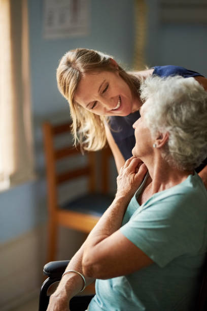 Devoted care and assistance Shot of a supportive daughter taking care of her senior mother in wheelchair at nursing home physical therapist photos stock pictures, royalty-free photos & images