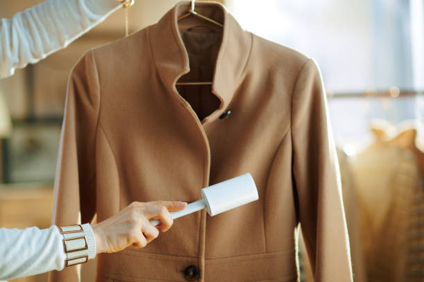 plan rapproché sur le manteau de nettoyage de femme au foyer sur le cintre avec le rouleau de peluche - lint remover photos et images de collection