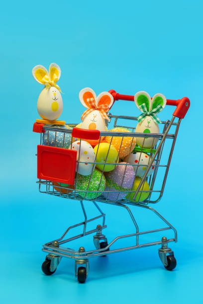 istock Easter bunny and eggs in the Shopping cart on blue background 1209870617