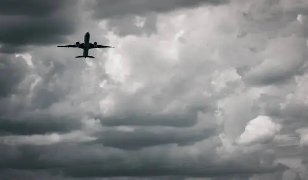 Photo of Airplane flying on dark sky and white clouds. Commercial airline with dream destinations concept. Aviation business crisis concept. Failed journey vacation flight. Air transportation. Sad travel.