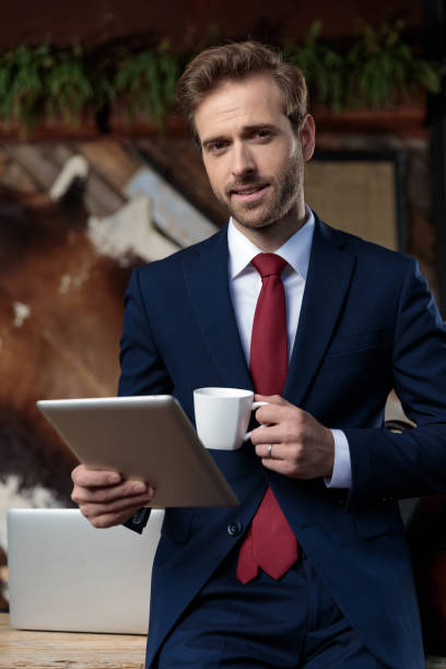 istock sexy businessman drinking coffee and holding tab 1209874247