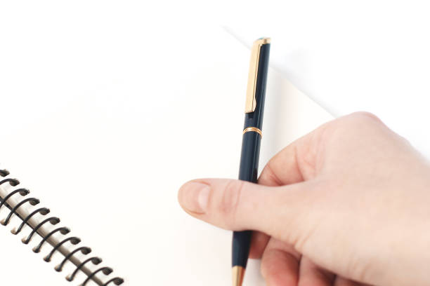 istock Pen in hand and notebook on a white background 1209876703