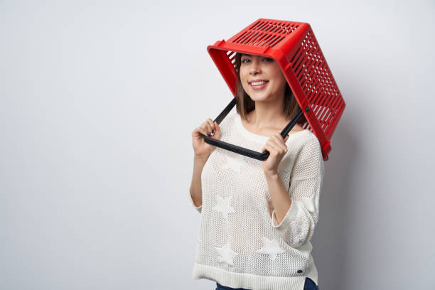 Crazy woman putting empty shopping basket on her head, looking at camera