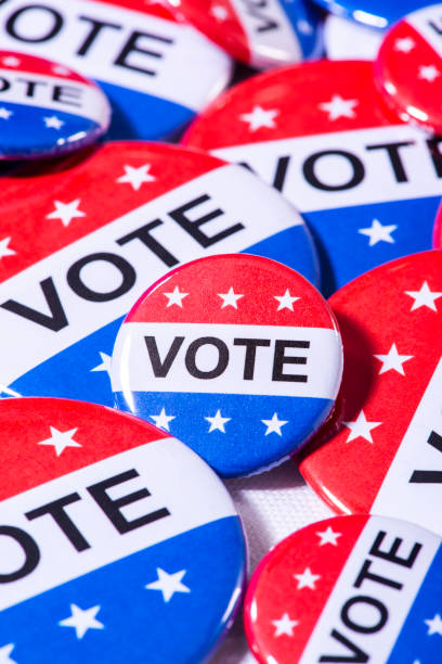 istock A bunch of various size red, white and blue VOTE buttons on a table 1209876964