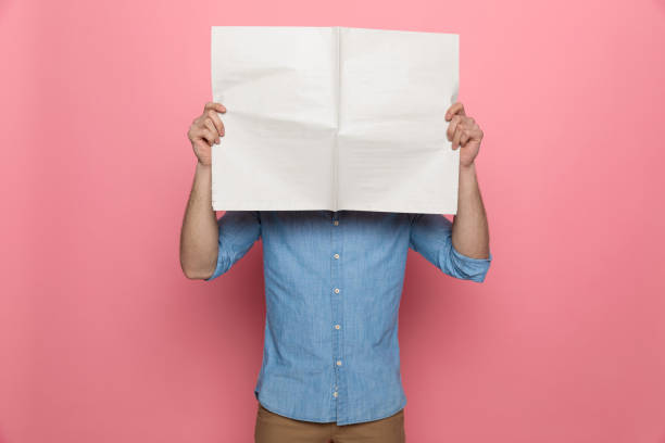 giovane ragazzo casual che copre il viso con il giornale - newspaper reading holding paper foto e immagini stock