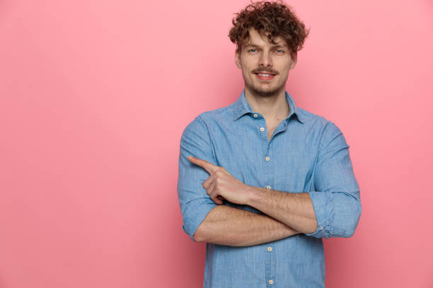 istock happy young guy smiling and pointing finger to side 1209878496