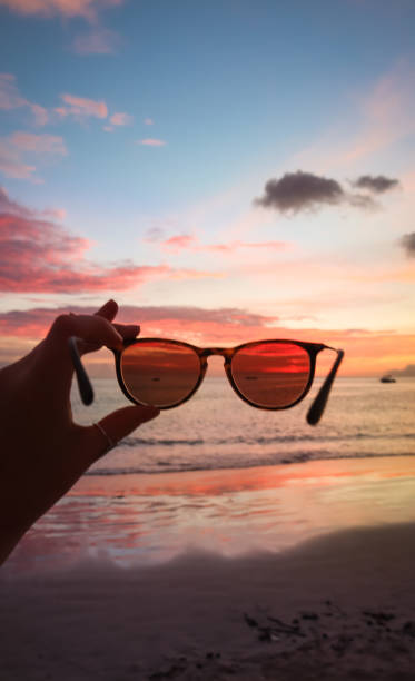 istock Hand holding sunglasses in Sunset 1209881230