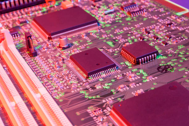 istock Motherboard of a computer slightly tilted and illuminated in blue and red light by different faces and with green dots at the nodes 1209881697