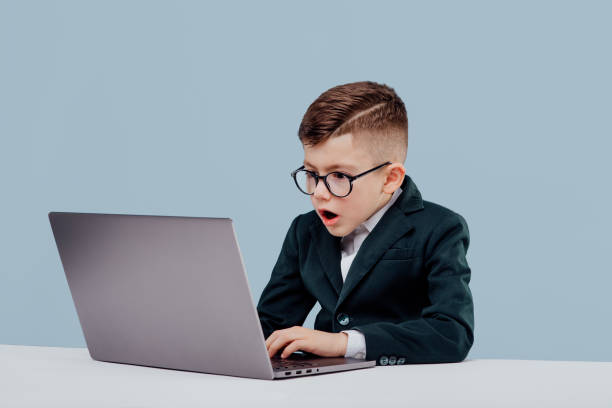 istock stressed little boy in suit and glasses  reading data from laptop while working on  project against blue background 1209885730