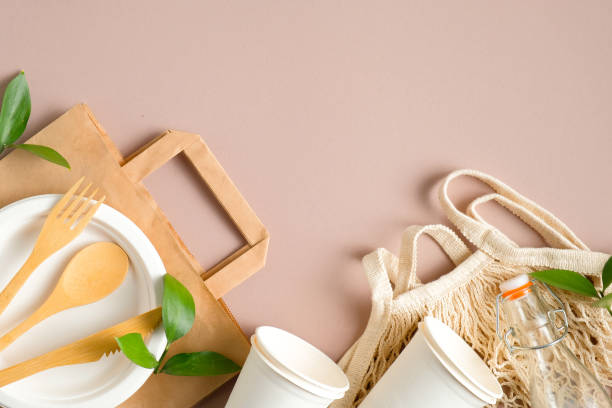 istock Plastic free set with biodegradable paper bag, wooden tableware, recycled drinking cups, glass bottle string bag, green leaves. Zero waste, eco friendly concept. Sustainable lifestyle. Top view. 1209886544