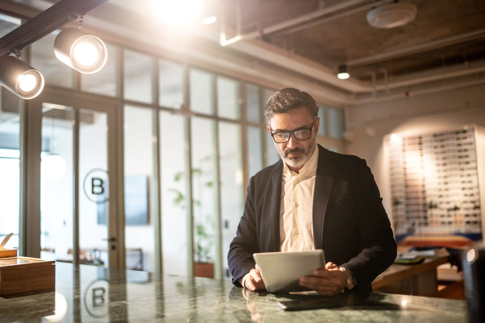 Mature businessman using digital tablet at modern office