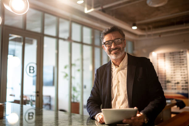 istock Portrait of mature businessman sitting using digital tablet at work 1209887620