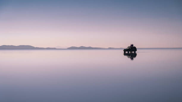 viaggiatori che esplorano le saline di uyuni all'alba in bolivia, sud america - dawn lake sky sunrise foto e immagini stock