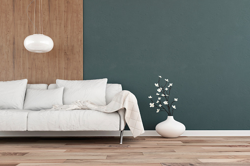 Elegant living room with white sofa on one side on hardwood floor in front of dark musk green plaster and hardwood wall with copy space.  Slight cross process added. 3D rendered image.