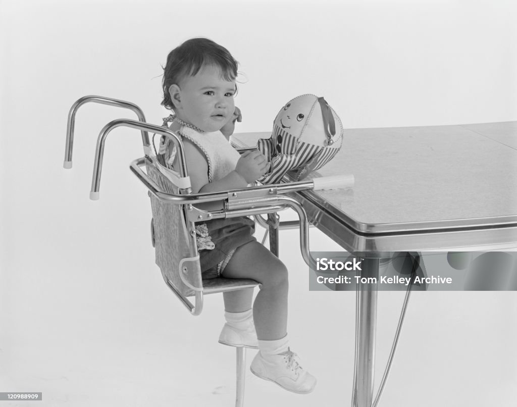 Bebê menina sentada na cadeira para bebê com brinquedos - Foto de stock de 1962 royalty-free
