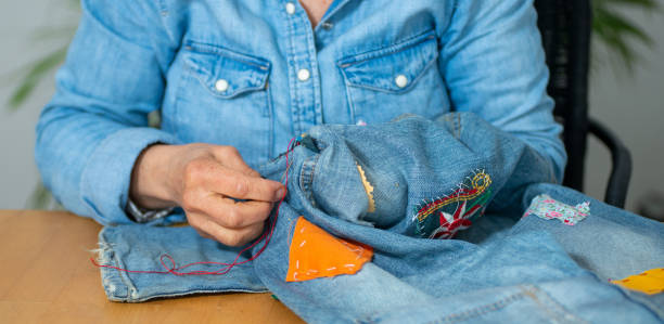 istock an elderly woman hands sewing on fabric jeans, 1209889306