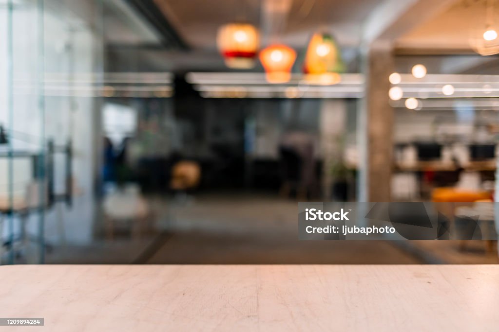 Wood table top and blurred bokeh office interior space background Wooden table in sunny office with big windows Office Stock Photo