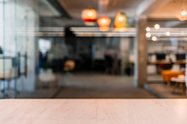 Wood table top and blurred bokeh office interior space background Wooden table in sunny office with big windows checkout photos stock pictures, royalty-free photos & images