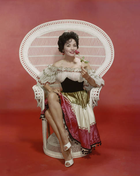 junge frau sitzt auf sessel holding rose, lächeln, porträt - 1950 1959 stock-fotos und bilder