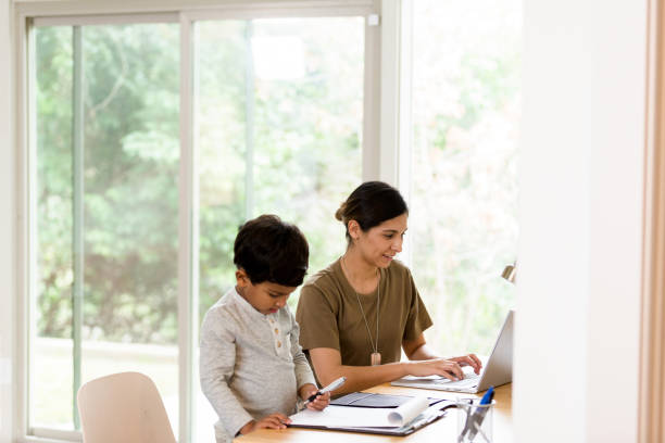 istock Military mother works on laptop while son draws nearby 1209896765