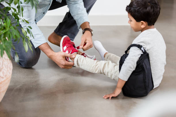 istock Boy waits patiently as unrecognizable dad helps with his shoes 1209896782