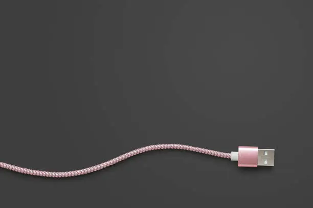 Photo of Pink USB cable on dark grey with clipping path