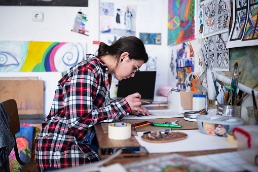 Young woman artist making mural painting projects in studio
