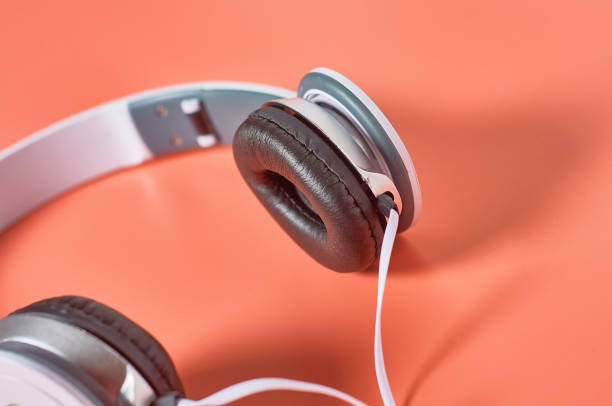 istock Modern white headphones with cable on orange background. Music concept 1209898993