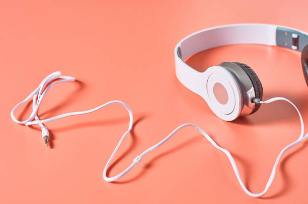 istock Modern white headphones with cable on orange background. Music concept. Copy space 1209898997
