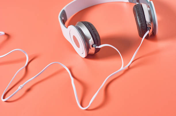 istock Modern white headphones with cable on orange background. Music concept 1209899001