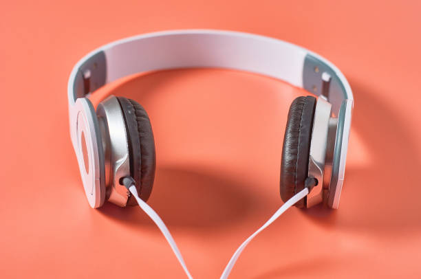 istock Modern white headphones with cable on orange background. Music concept 1209899002