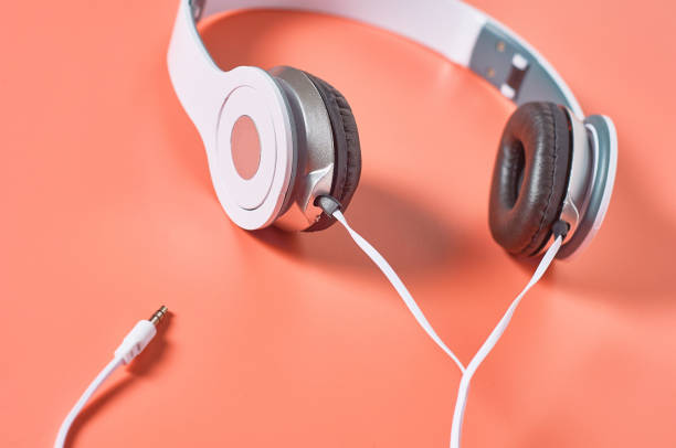 istock Modern white headphones with cable on orange background. Music concept 1209899007