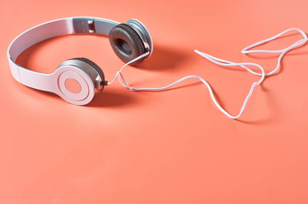istock Modern white headphones with cable on orange background. Music concept. Copy space 1209899013
