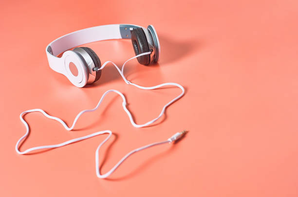 istock Modern white headphones with cable on orange background. Music concept. Copy space 1209899015