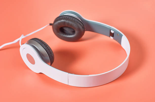 istock Modern white headphones with cable on orange background. Music concept 1209899025