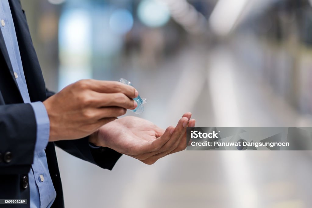 man hands using wash hand sanitizer gel dispenser, against Novel coronavirus or Corona Virus Disease (Covid-19) at public train station. Antiseptic, Hygiene and Healthcare concept Adult Stock Photo