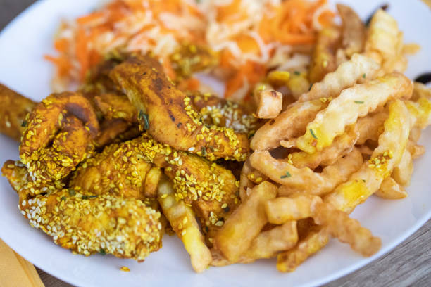 istock Breaded chicken meat with sesame over it, fried potatoes and salad on plate 1209904090