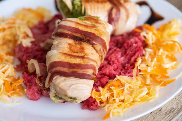 Stuffed chicken meat in wrapped bacon and salad in plate, close-up