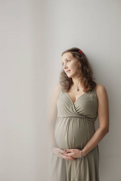Portrait of pregnant woman standing near the window and touching her big belly. Waiting for the baby. Motherhood. Image of happy pregnant European woman with big tummy is relaxing. Pregnancy, motherhood, people and expectation concept. Complete family. olivia mum stock pictures, royalty-free photos & images